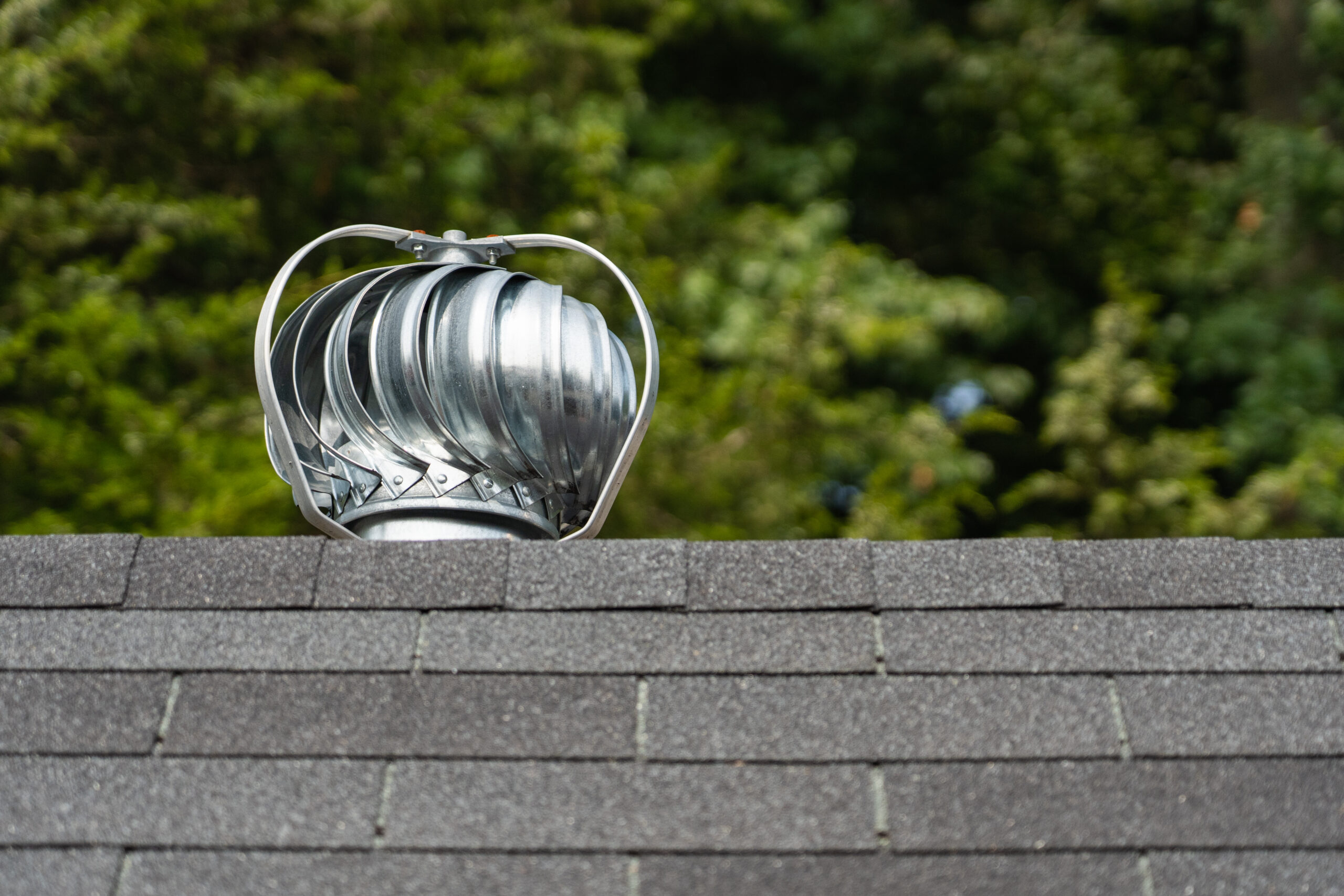 Turbine ventilator on top of a roof uses wind power to exhaust heat and moisture from the attic.