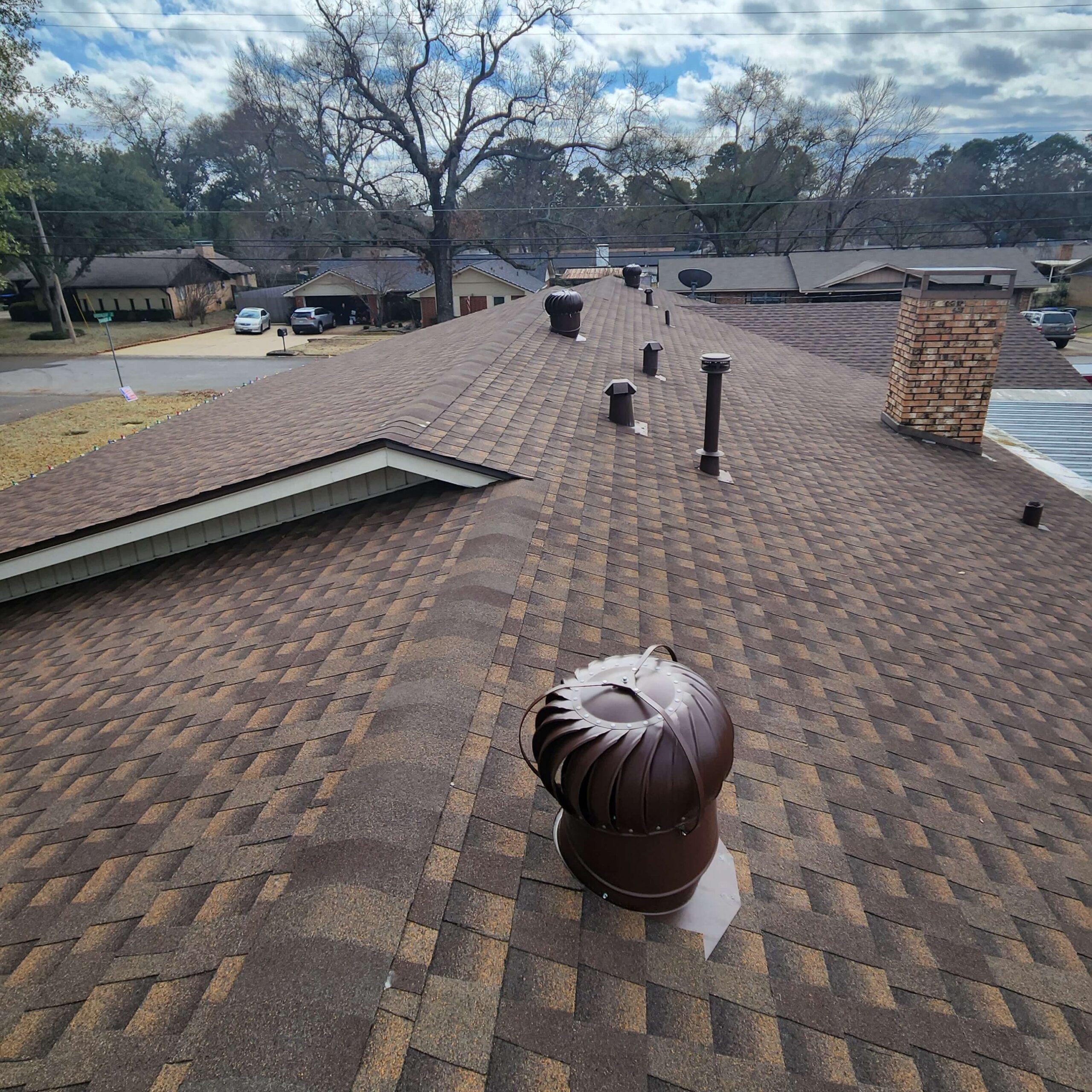 Asphalt shingle roof with vents and a chimney on a residential home.